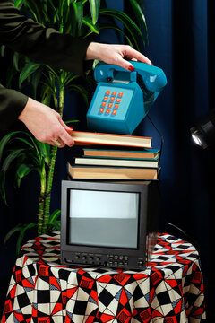 Vintage office studio setup with a stack of books, a retro telephone, and a monitor on a patterned tablecloth