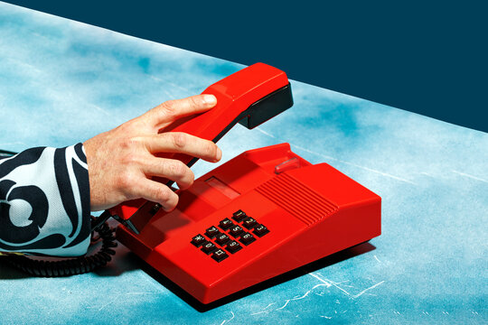 Caucasian male making a call with a retro red telephone