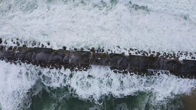 Huge waves crashing over Breakwater during winter storm Atlantic waves washing the lighthouse on Praia da Aguda sandy beach at Aguda settlement near Porto, Portugal. TOP view 4K flying drone video.
