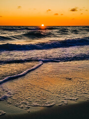 A picturesque sunset over the Baltic sea on a summer day in Liepaja, Latvia. The setting sun over the waves.