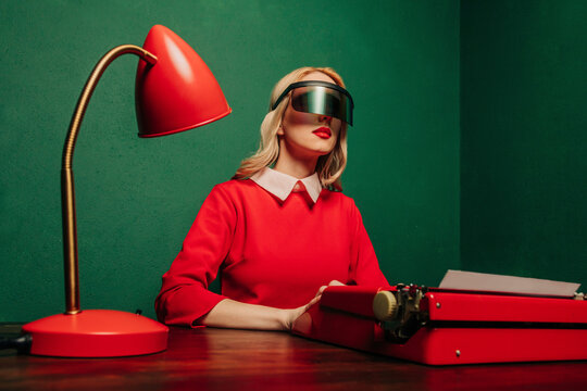 Woman in red dress with VR glasses at a typewriter in a stylish office