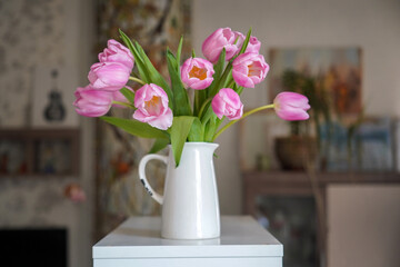 pink spring flowers in white ceramic vase in modern home interior