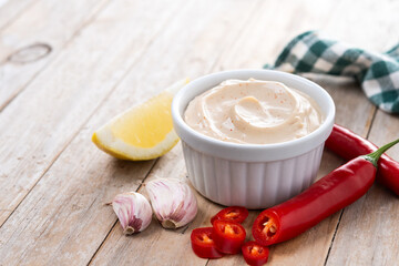 Chipotle sauce and spices in bowl on wooden table. Copy space