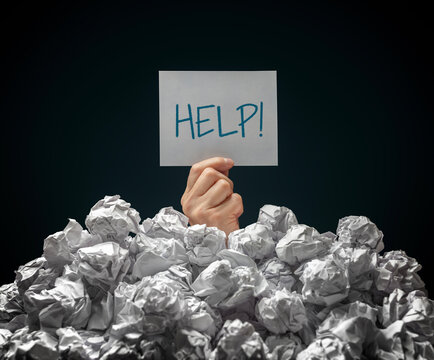 Help sign held up by man buried under crumpled pile of paperwork papers with black background - Powered by Adobe