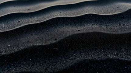 Black Sand beach macro photography. Background, texture, wave pattern of oceanic sand on the beach, black. Texture of beach sand. Black beach.