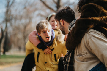 A group of young friends having fun and enjoying a piggyback ride outdoors in an autumn park. Joy, companionship, and laughter are the main themes of this vibrant outdoor image.