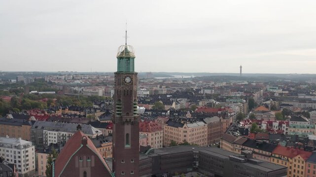 Engelbrektskyrkan in &Ouml;stermalm, Stockholm, Sweden during cloudy sunset in the summer. Aerial shot panning left with the church in the foreground and skyline, buildings and rooftops in the background.