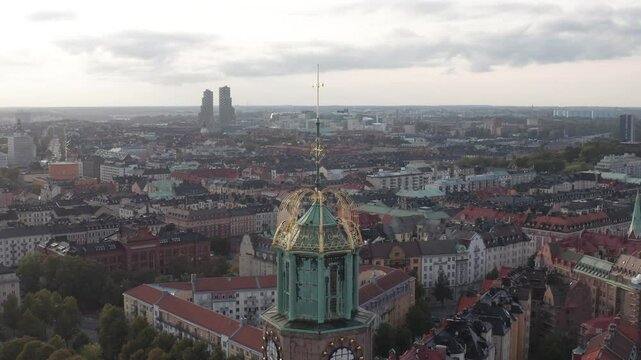 Engelbrektskyrkan in &Ouml;stermalm, Stockholm, Sweden during evening. Aerial shot lowering while tilting upwards with top of church in foreground, skyline in background with Norra Tornen visible.
