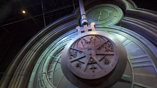Giant, ornate pendulum swings on clock face. Dutch angle.