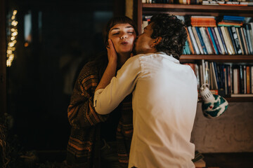 A cozy domestic scene of a couple laughing together, with bookshelves in the background.