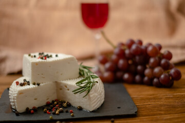 Goat cheese, grapes and wine lie on a wooden table. Cheese at home.