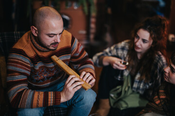 A group of friends enjoy each other's company, sharing stories and engaging in meaningful projects around a cozy indoor setting, fostering connection and a warm atmosphere.