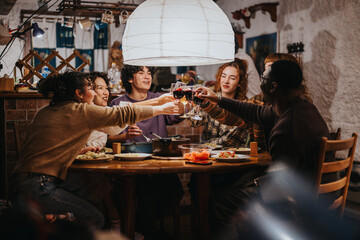 A cheerful group of friends sit together at a dinner table, sharing food and laughter while enjoying a cozy evening indoors. The atmosphere reflects warmth, companionship, and the joy of gathering.