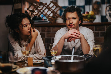 A man and a woman seated indoors at a bar sharing a thoughtful moment. Their interaction conveys a mix of casual and reflective tones, with drinks and food interspersing their setting.