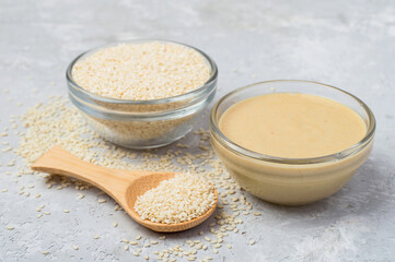 Raw sesame seeds and sesame paste on a gray concrete background. Horizontal.