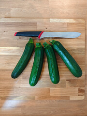 Freshly harvested zucchinis arranged with a sharp knife on a wooden cutting board ready for culinary creativity