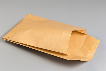 Open light brown paper mailing packing bag on gray background