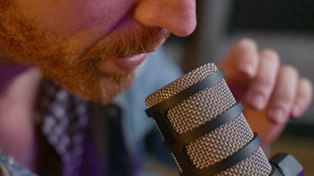 Close-up of a man speaking into a professional dynamic microphone in a podcast or recording studio. Guy podcasting or broadcasting, voiceover work, streaming, radio, and ASMR content creation
