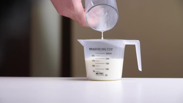 Chef pouring milk into measuring cup for recipe preparation