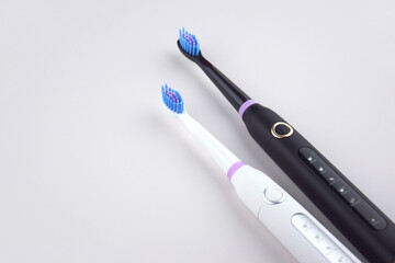 Modern electric ultrasonic toothbrush with rechargeable battery on a gray surface.