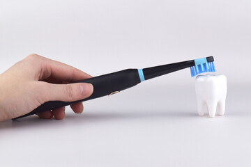 Modern electric ultrasonic toothbrush with rechargeable battery on a gray surface.
