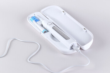Modern electric ultrasonic toothbrush with rechargeable battery on a gray surface.