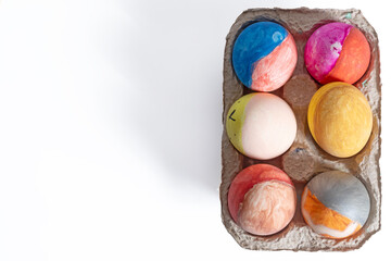 Colorful decorated Easter eggs in a cardboard box on a white background