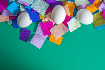 Happy Easter. White eggs with colored crepe paper on green background with copy space.