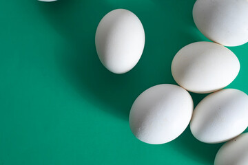 Overhead view of white eggs on a vibrant green background.