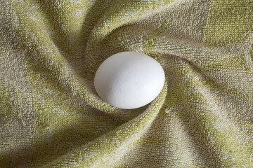 White egg on green cloth with natural light, top view