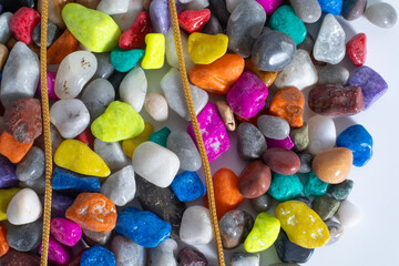 Gold chain on top of different colored stones on white background
