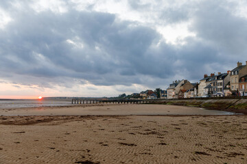Sunrise view of coastal street of Grandcamp Maisy, a scenic French coastal town in Normandy, with fishing port, sandy beaches, and maritime traditions.