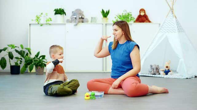 Baby Sign Language. Nonverbal child learning to sign with the help of a speech therapist. Child therapy, neurodiversity, learning difficulty, developmental disability.