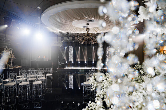 Banquet hall decor for a wedding. White flowers, mirrors and lighting. table setting and services of professional event organizers. 