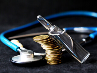 Ampoule with medicine, stack of coins and stethoscope, medical theme.