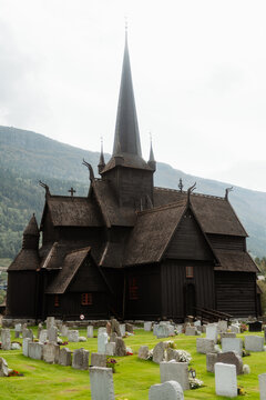 Historic Lom Stave Church with traditional stone fence and mountain backdrop, Norway