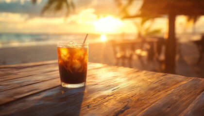 A beautifully captured image of an iced coffee sitting on a wooden table at a beachside caf&eacute; during sunset.