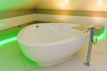 a room with a large massage bathtub with multi-colored lighting. bathroom interior.