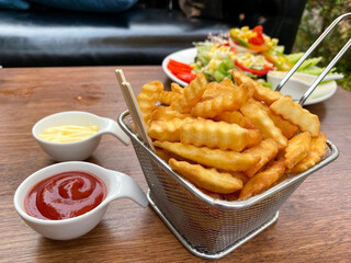 French fries in a basket, served with ketchup and mayonnaise