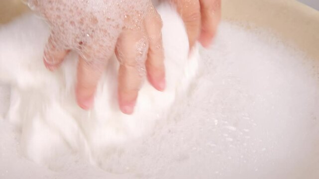female Hands immersed in soapy water, gently scrubbing fabric clean, Nostalgic scene traditional laundry methods in modern times, Domestic chores