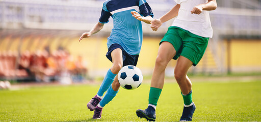 Soccer players kick the ball in competition. Football adult game. Players in two teams compete for the ball. Footballers running on the grass pitch