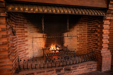 a large old brick fireplace with metal grates and a fire burning in it