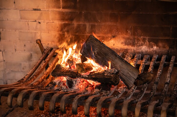 a large old brick fireplace with metal grates and a fire burning in it