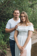 Obraz premium Romantic couple kissing and embracing near a lake and forest on a cloudy day.