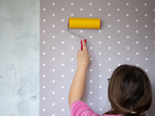 girl glues wallpaper in children's room, girl does repairs with her own hands