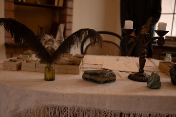 .A vintage study table with an ornate candle holder, mineral specimens, quill pens, and old...