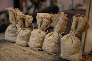 A row of small burlap sacks tied with twine, arranged on a rustic wooden surface, evoking a sense of vintage agriculture, traditional packaging, or organic storage.