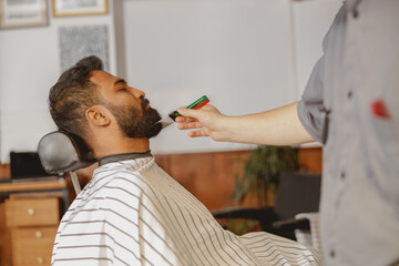 A man is enjoying a meticulous beard trim at a barber shop that provides professional grooming care