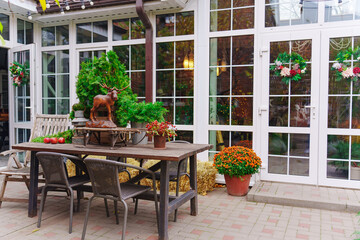 a wooden table and benches in the courtyard of a private house. stylish landscape design of the garden. garden furniture. wooden moose figurine