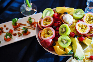Plate with sliced exotic fruits on the banquet table. A healthy dessert at a buffet table.